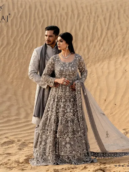 Here, I created a coordinated look that feels both ethereal and grounded. The groom's light grey sherwani, with its subtle all-over embroidery, perfectly complements the bride's intricately detailed grey gown, creating a harmonious vision against the desert sands.