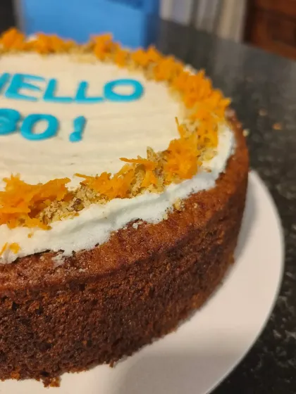 A close-up on the texture of the carrot and dates cake, garnished with grated carrots and walnuts.