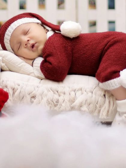 A full-body shot of the baby in a Santa outfit, nestled in soft white fluff. We prioritize your baby's comfort and warmth during all our sessions.