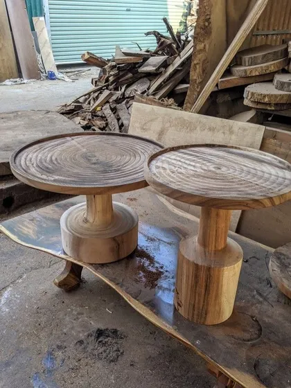 A pair of solid wood side tables with carved, concentric circles on top.