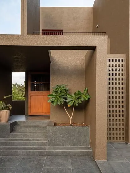 The entrance to the 'H-House' is a study in minimalist geometry, with intersecting planes of textured concrete creating a sheltered and intriguing threshold.
