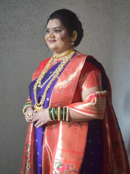 A side profile of the bride, showing the elegant fall of her Paithani saree and her graceful posture.