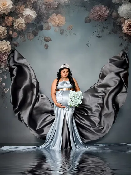 A creative portrait using a silver-blue satin gown to create beautiful, flowing shapes against a floral backdrop. The added water reflection effect gives the image a dreamy, ethereal quality.