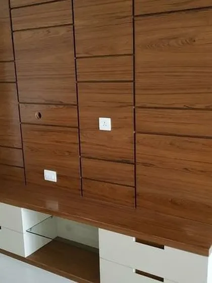 This custom TV unit features a unique textured wood panel design with concealed storage. The two-tone finish with white drawers adds a modern touch while providing ample space for media devices.