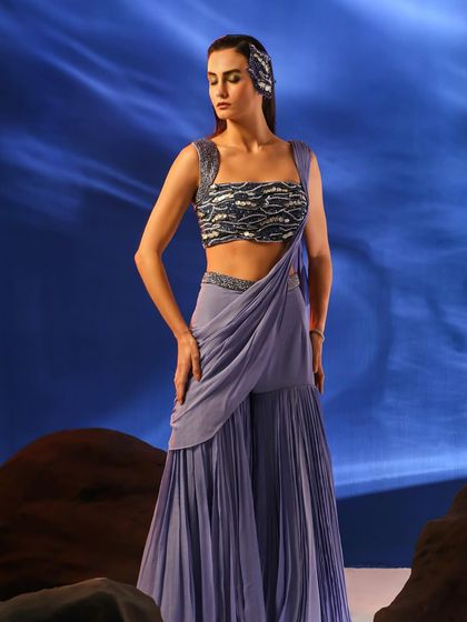 Another angle of the lavender sharara set, showing the full silhouette against the dramatic backdrop. The styling is consistent with the collection's ethereal theme.