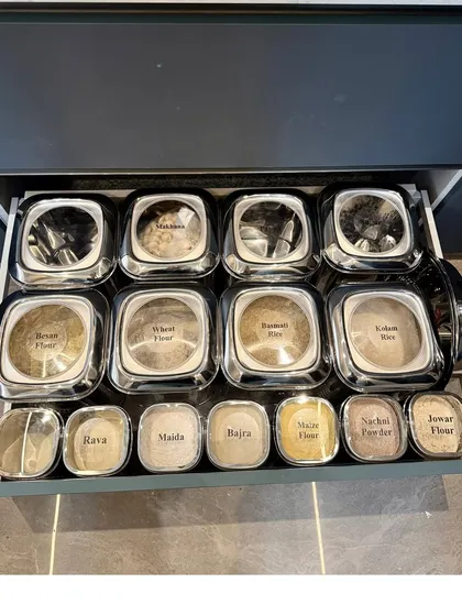 This drawer contains a complete assortment of Indian flours, each in a labeled steel container. This durable and stylish solution is perfect for keeping flours fresh and organized.