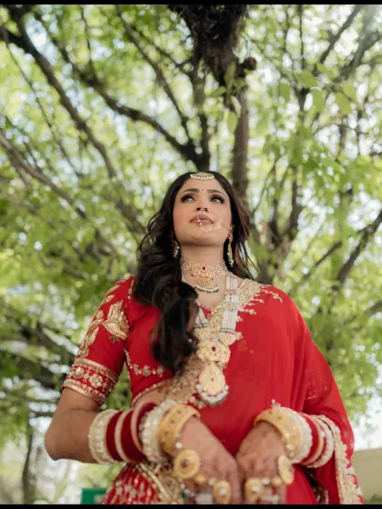 A low-angle shot of the bride looking up, with the green canopy of a tree framing her. It's a powerful and hopeful portrait.