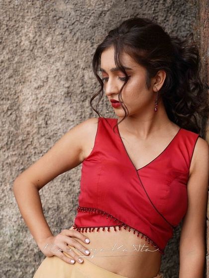 The red crop top features a delicate, beaded hemline and a flattering wrap-style design.