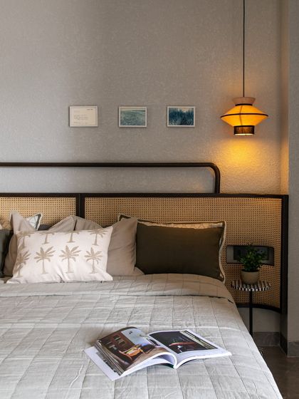This bedroom feels like a deep exhale. The palette is neutral, but the textures of the rattan headboard, quilted bedspread, and the warm glow of the pendant light make it feel anything but boring.