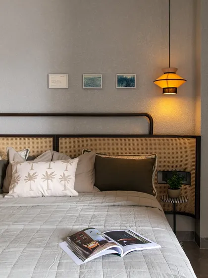 This bedroom feels like a deep exhale. The palette is neutral, but the textures of the rattan headboard, quilted bedspread, and the warm glow of the pendant light make it feel anything but boring.