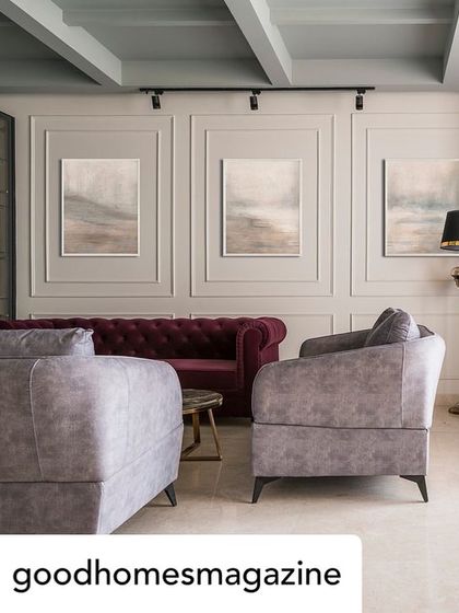 This living room from a featured project shows an English-inspired design with floor-to-ceiling wainscoting and a mix of vibrant and neutral upholstery. The coffered ceiling adds architectural depth to the space.