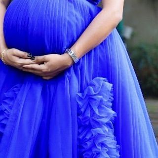 A detail shot focusing on the ruffled texture of the royal blue maternity gown, showing how the design adds volume and interest to the silhouette.