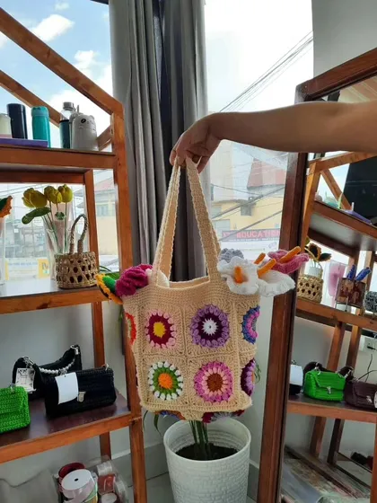 This photo shows my multi-color granny square tote bag in my workspace. It highlights the bag's bright colors and handmade texture against the backdrop of my craft supplies, giving a glimpse into where your bag is made.