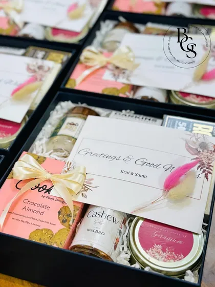 A sophisticated thank you gift. This dark gift box is filled with a curated selection of treats and a scented candle, adorned with a personalized card and delicate dried flowers.