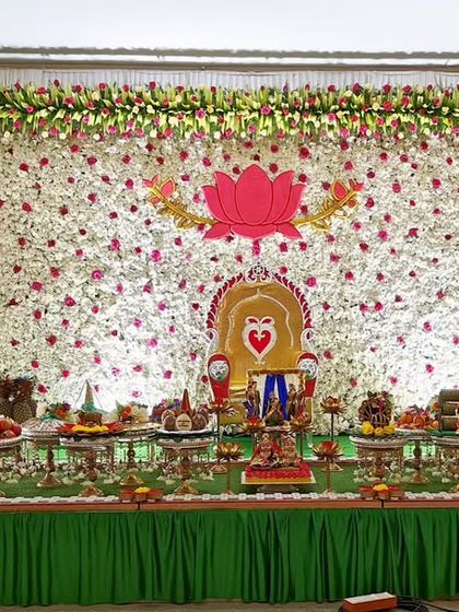 A baby shower setup with a green and white floral backdrop, featuring a large lotus motif and a full display of traditional plates.