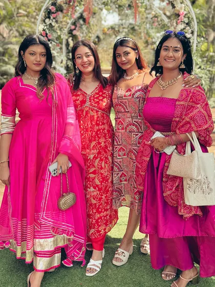 A group photo with friends at an outdoor wedding event. Everyone is dressed in vibrant colors, showcasing different styles of Indian wedding guest attire.