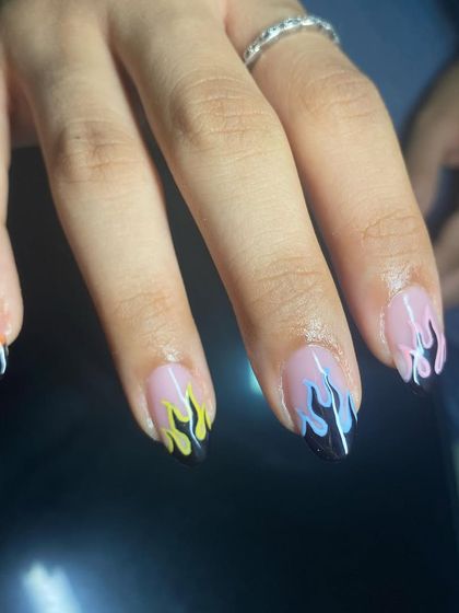 Bringing the heat with these colorful flame nails. Each nail has a different pastel flame design hand-painted over a black tip.