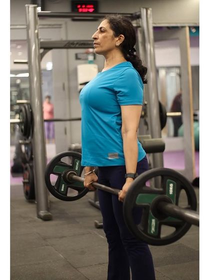 A member holds a deadlift at the top position, demonstrating the strength built through consistent training.