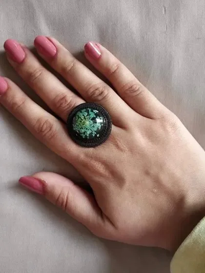 This adjustable ring features a Queen Anne's lace flower against a dark background. The intricate pattern of the flower is beautifully highlighted in this piece.