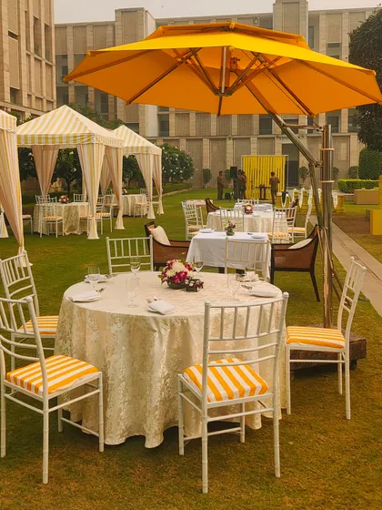 A classic round dining table with a large yellow umbrella, part of the chic brunch setup. I use a mix of seating arrangements to create a dynamic event space.