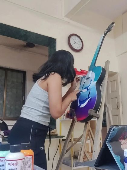 Focused on the details. Here I'm painting a dreamy whale and ocean scene on the body of the guitar.