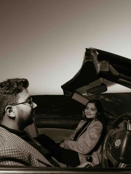 A sepia-toned shot from inside the car, capturing a sweet, smiling interaction between the couple.