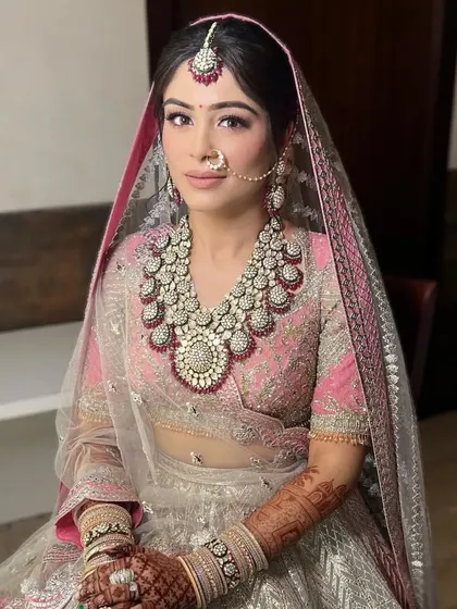 A bride seated in her stunning Falguni Shane Peacock lehenga, her hair styled in a soft, textured updo with a few fresh flowers. This hairstyle is perfect for a modern yet traditional bridal look.