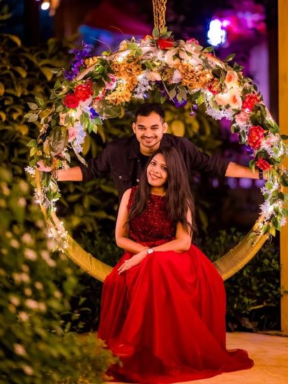 A romantic evening shoot on a floral swing. The client's red sequin gown shimmers in the light, creating a magical and festive atmosphere.