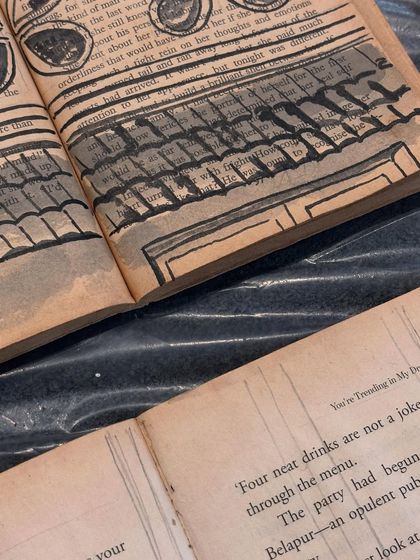 A close-up detail of the book art, showing the texture of the paper and the ink sketch of roof tiles, blending the printed text with the new visual narrative.