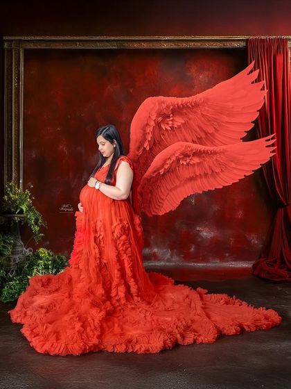 A full-length view of our red angel wings and ruffled gown. This studio setup is perfect for creating a bold, artistic, and unforgettable maternity portrait.