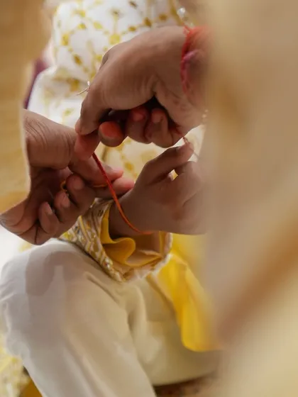 A close-up of a sacred thread being tied, a significant ritual during the pre-wedding ceremonies. We pay close attention to every traditional detail.