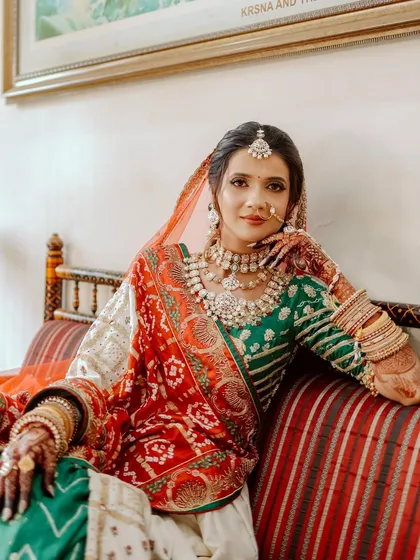 The complete royal look of a Gujarati bride. The makeup is balanced to work with the vibrant colors and heavy jewelry of her traditional panetar.