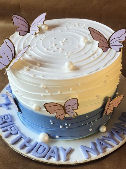 A whimsical butterfly cake with a blue ombre effect, decorated with delicate paper butterflies that seem to flutter around the cake.