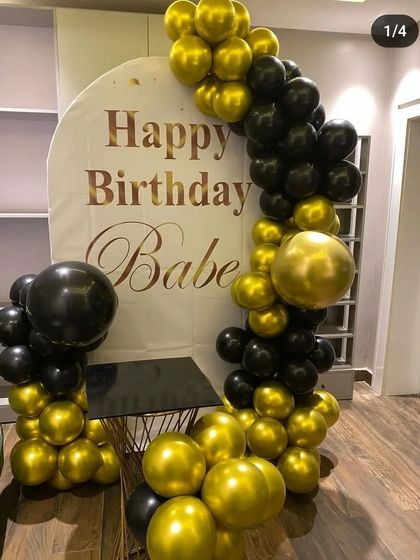 Another view of the black and gold birthday setup, showing the addition of a small table, perfect for placing a cake or gifts within the decorated photo area.