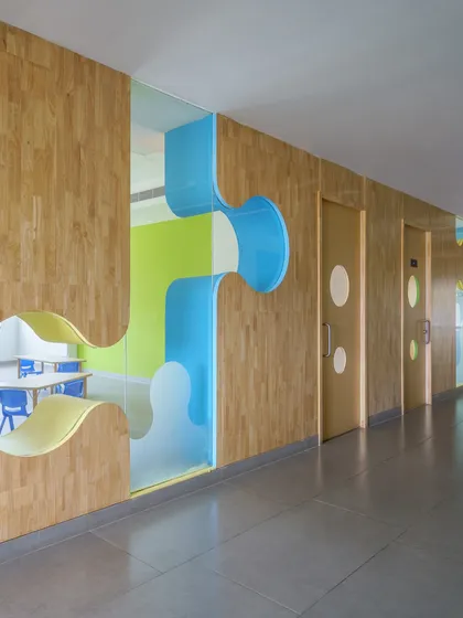 The completed corridor at Amity International School, Mohali, bringing the render to reality. The final space captures the playful vision, with wooden walls, puzzle-piece windows, and vibrant colors.