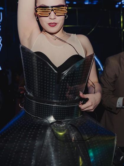 An interactive performer in a futuristic, illuminated dress mingling with the guests, adding to the dramatic and unconventional vibe of the Sangeet.