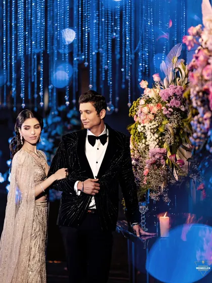 A stylish portrait of the couple amidst floral decorations, the blue lighting and bokeh effect creating a dreamy atmosphere.