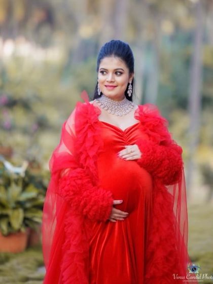 A truly regal look for a mom-to-be. This combination of a red velvet gown and a dramatic ruffled tulle robe creates a luxurious and high-fashion maternity portrait.