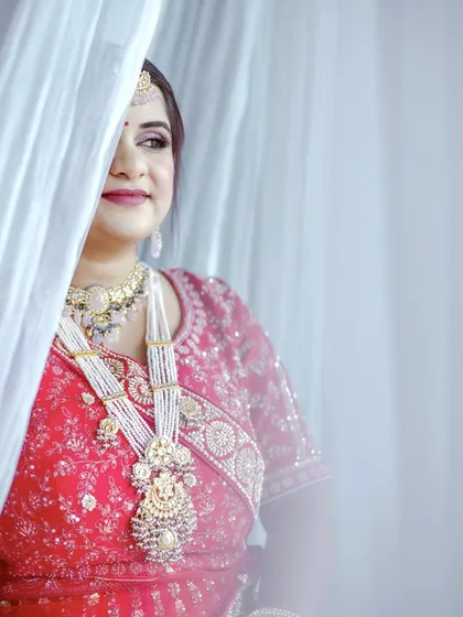 A peek-a-boo shot of the bride from behind a white curtain. This playful portrait is both artistic and charming.