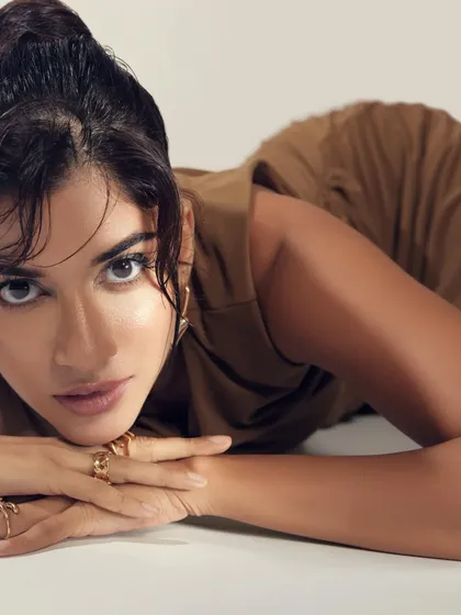 Transitioning to a more golden, earthy-toned look in the same shoot. The makeup is flawless and fierce, with a focus on radiant skin.