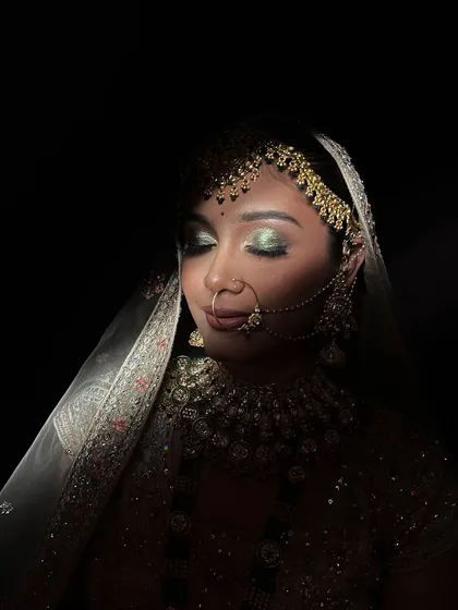 An artistic shot using shadows to highlight the intricate eye makeup and bridal jewelry.