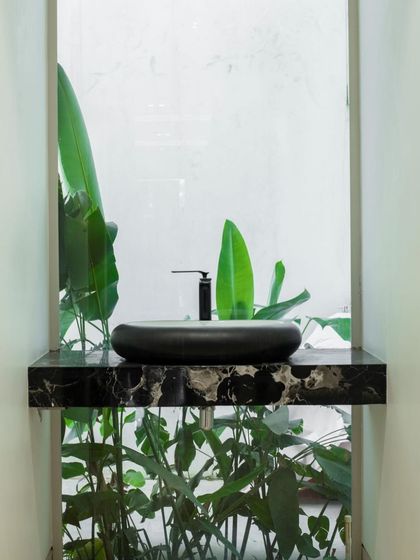 A minimalist powder room where the sink is set against a window overlooking a private green space. This design brings a touch of nature indoors, creating a refreshing and serene experience.