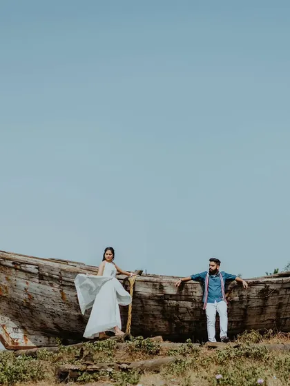 A wide-angle shot of a couple posing on a rustic, abandoned boat in Alibag. This unique prop adds a powerful, story-driven element to their beach pre-wedding shoot.