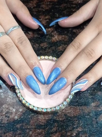 A shimmery blue cat-eye set with abstract white swirls on accent nails.