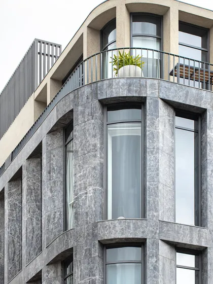 A detailed view of The Afyon Pavillion's facade, where curved walls clad in Afyon Grey marble create a sense of fluidity and elegance. This choice of material and form breaks the monotony of a typical commercial building, adding a layer of visual sophistication.