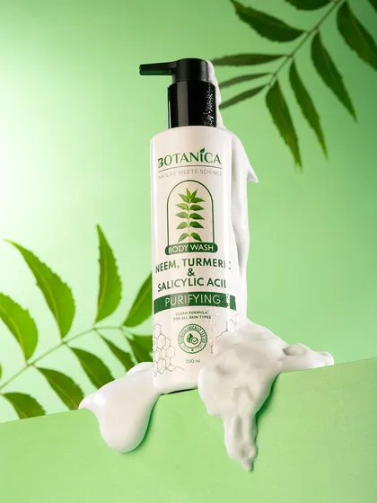 A shot of a purifying body wash with a rich lather texture. The fresh green background and neem leaves visually reinforce the product's natural, purifying ingredients.