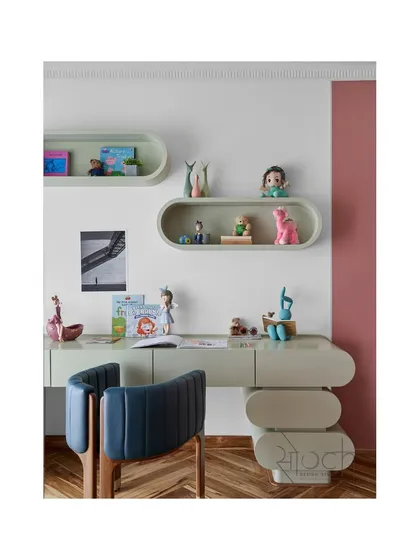 The custom study desk in the daughter's room features a unique, bubbly shape and is paired with a comfortable blue chair. The design is both fun and functional, encouraging creativity.