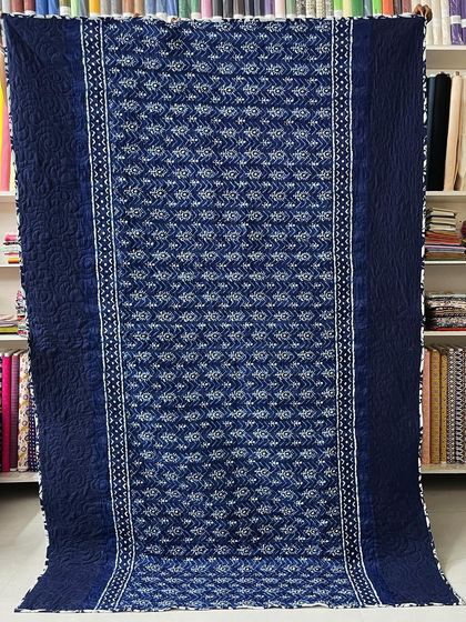 The back of a beautiful indigo saree quilt, showing how the quilting pattern creates a subtle, elegant texture.