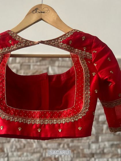 A detailed view of the back of the quintessential red blouse, featuring a large square cutout with meticulously embroidered borders.