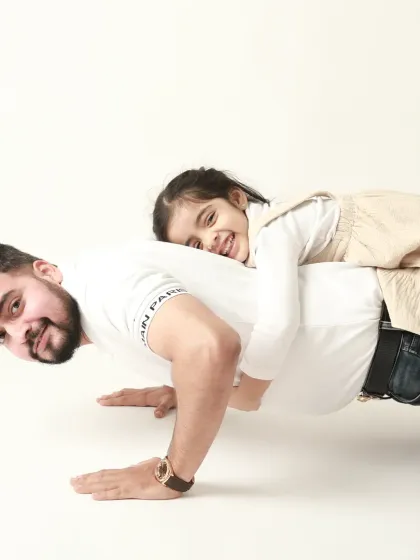 A father's strength is his child's playground. This playful shot of a daughter riding on her dad's back as he does a push-up is full of fun and trust.